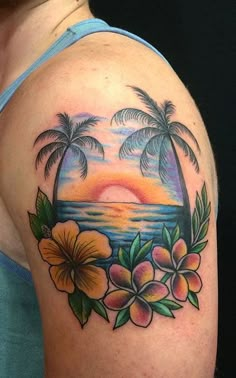 a woman's shoulder with flowers and palm trees on the beach in front of it