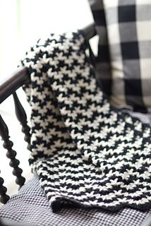 a black and white blanket sitting on top of a chair next to a pillow with hounds