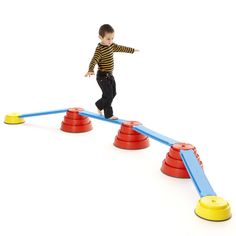 a young boy standing on top of two red and blue cones next to an obstacle