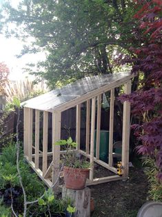 a small wooden shed sitting in the middle of a yard with potted plants on it