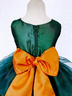 a green and orange dress with a big bow