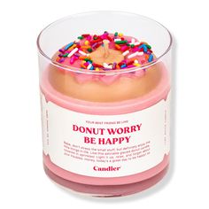 a pink candle with sprinkles and donut worry written on the top