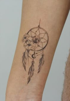 a woman's arm with a small dream catcher tattoo on the left side of her leg