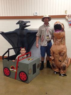 a man standing next to a child in an inflatable dinosaur with a cart