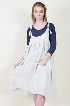 a woman standing in front of a white wall wearing a blue and white striped dress