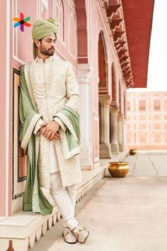 a man in a white and green outfit leaning against a wall