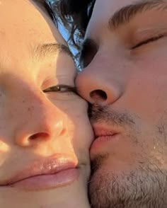 a man and woman kissing each other while the sun shines on their faces behind them