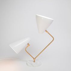 a white table lamp sitting on top of a white wall next to a light bulb