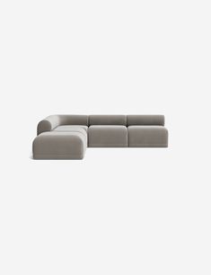 a gray sectional couch sitting on top of a white floor next to a black chair