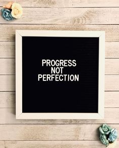 a framed sign that says progress not perfectionion on it next to some succulents