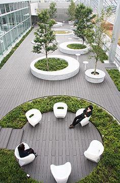 two people sitting on white chairs in the middle of a circular area with trees and grass