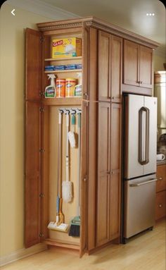 an organized kitchen with wooden cabinets and stainless steel appliances in the corner, along with cleaning supplies