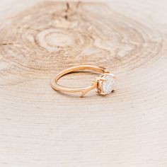 a gold ring with a single diamond on it sitting on top of a tree stump