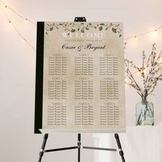 a wedding seating sign on a tripod with lights in the background