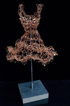 a sculpture made out of wire on top of a wooden block in the middle of a dark room