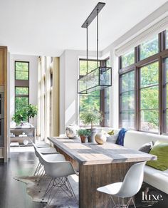 a living room filled with furniture and windows next to a kitchen counter topped with potted plants