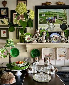 a kitchen counter topped with plates and vases filled with green flowers on top of it