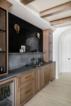 a kitchen with wooden cabinets and marble counter tops, along with wine bottles on the shelves