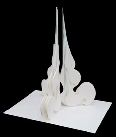 three tall white sculptures sitting on top of a piece of paper