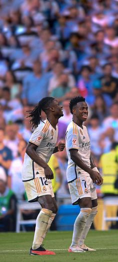 two soccer players standing on the field with their hands in each other's pockets