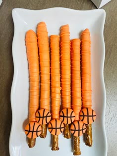 carrots with basketball decorations on them sitting on a white plate, ready to be eaten