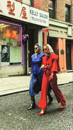 two women walking down the street in front of a store