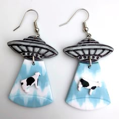 pair of earrings with black and white cow on blue background