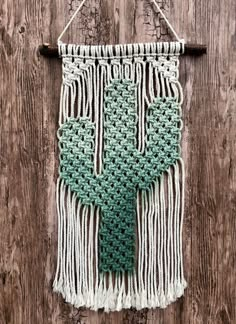 a green and white crocheted wall hanging on wooden planks with string attached to it