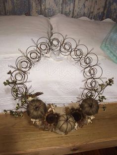 a wreath made out of wire sitting on top of a wooden table next to a bed