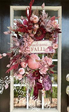 a welcome fall door hanger with pink flowers and leaves in front of a wooden door