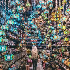 a woman walking through a store filled with lots of colorful lights hanging from the ceiling