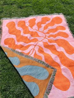 an orange and pink rug laying on the grass