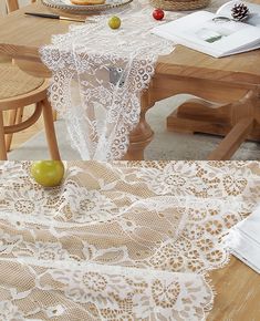 the table is covered with white lace and has apples on it, along with other items