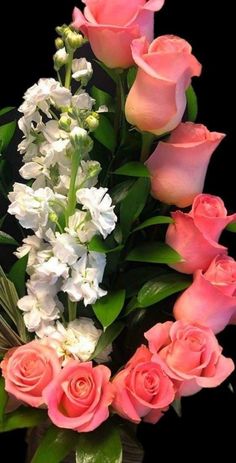 a vase filled with pink roses and white flowers