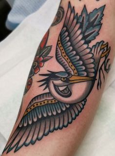 a close up of a person's arm with a bird tattoo on the arm