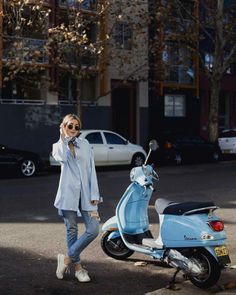 a woman standing next to a scooter talking on a cell phone