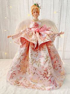 an angel figurine with pink and gold leaves on it's wings, wearing a tiara