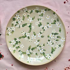 a plate with flowers painted on it sitting on a pink table cloth next to some red and white confetti