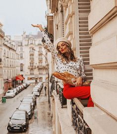 a woman standing on the ledge of a building with her arms outstretched in the air