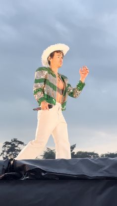 a man in white pants and a green striped shirt is on top of a roof