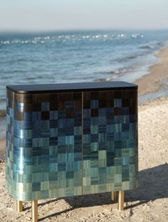 a blue and green cabinet sitting on top of a sandy beach next to the ocean