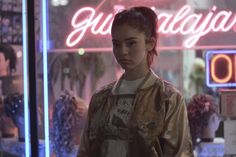 a woman standing in front of a neon sign