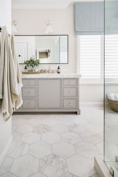 a bathroom with marble flooring and white walls, along with a large mirror on the wall