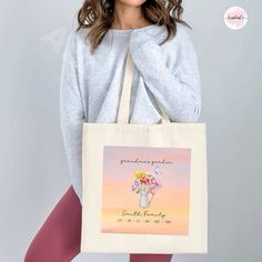 a woman holding a tote bag with flowers in it and the words grandma on it