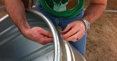 a man in green shirt holding onto a metal barrel