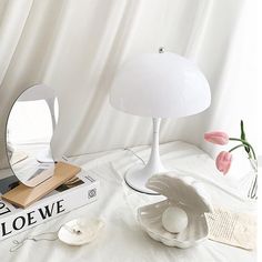 a white lamp sitting on top of a table next to a mirror and bookend