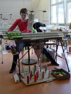 a woman sitting at a table working on an electronic device in a room filled with bottles and tubes