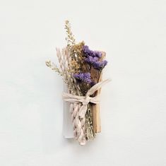 dried lavenders tied up in twine on a white background with some brown and purple flowers