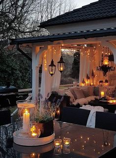 an outdoor dining area with candles lit up on the table and lights hanging from the roof