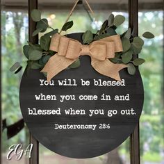 a sign with a bow hanging from it's front door saying, you will be blessing when you come in and blessed when you go out